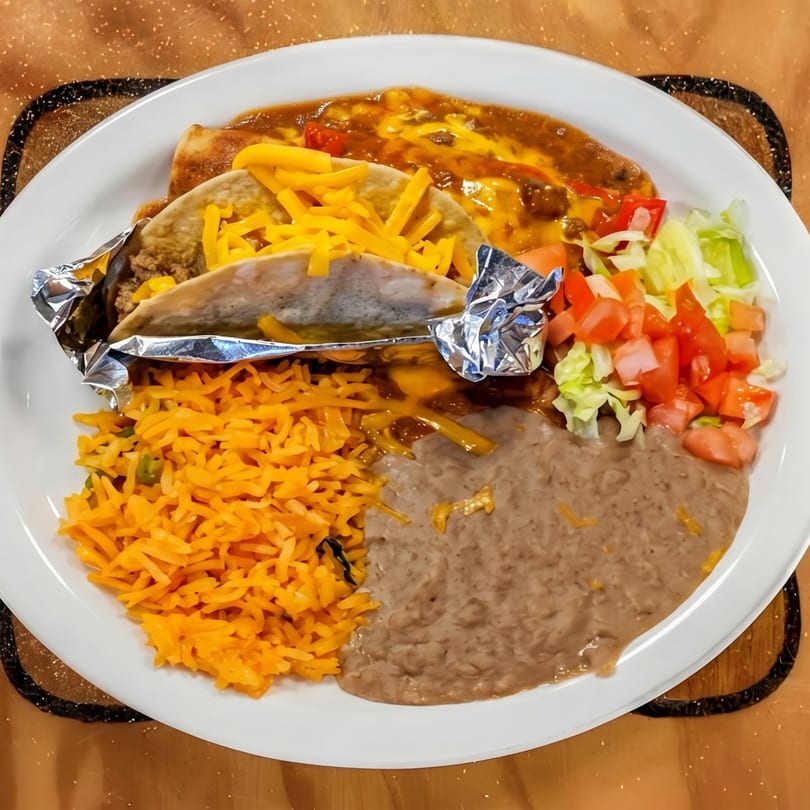 A Mexican combination plate with a taco, enchilada, rice, refried beans, and salad.